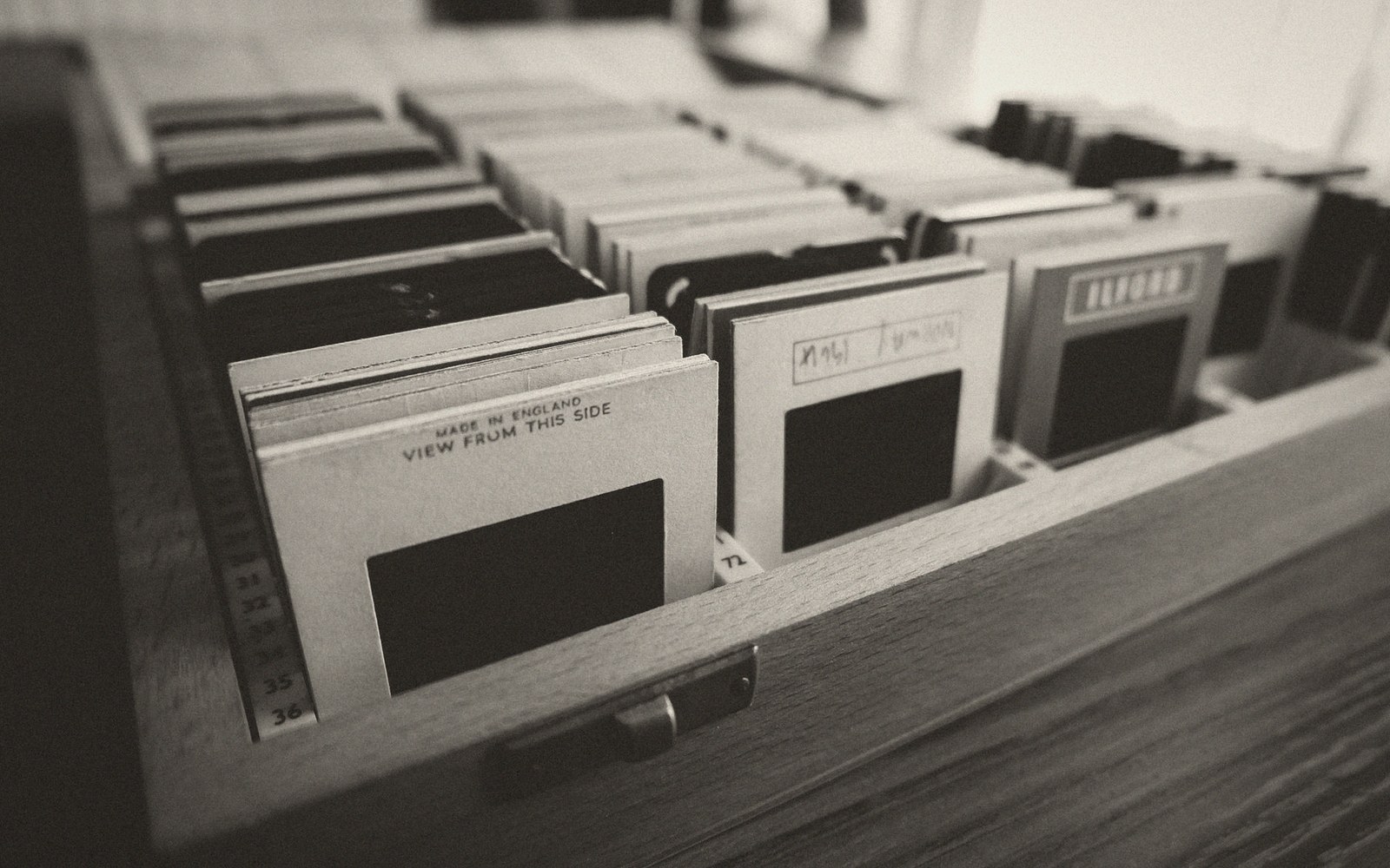 Rows of cardboard-mounted photo slides stored upright in a wooden drawer