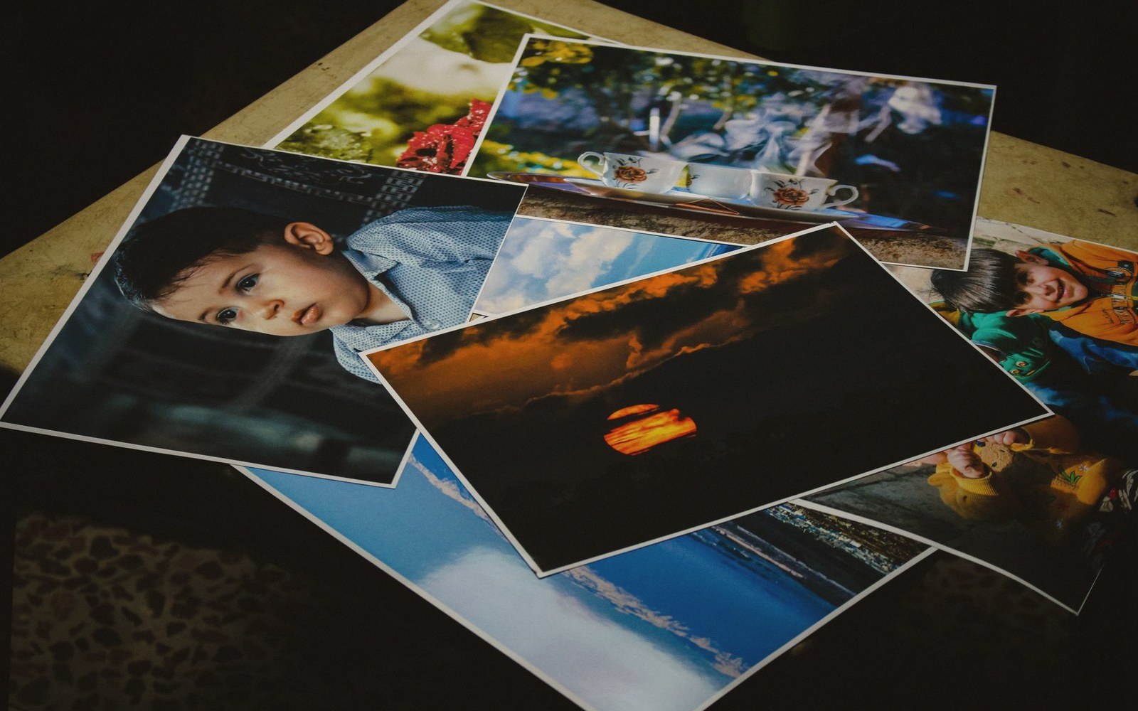 Printed photographs of a child, a sunset and tea cups scattered on a table