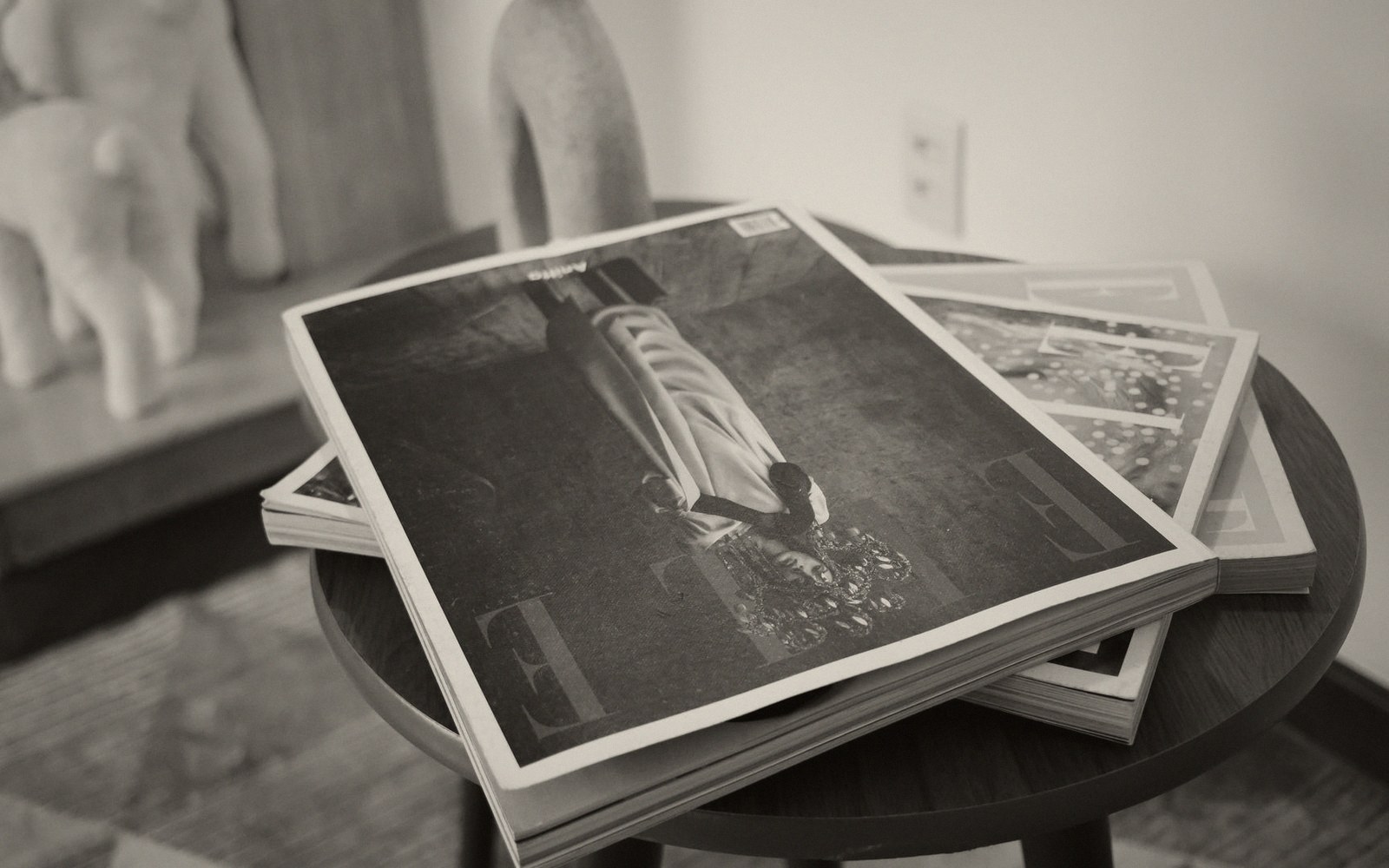 Stack of magazines with a cover portrait resting on a round side table